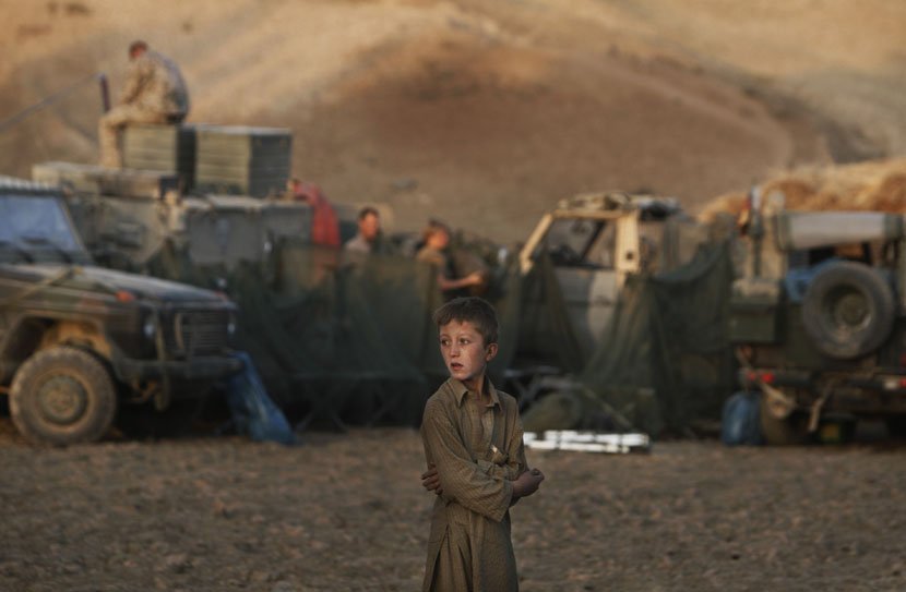 Avganistanski dečak gleda u nemačke vojnike dok prave privremeni kamp za noćenje u Avganistanu 2009.