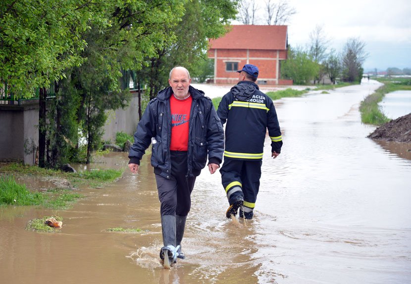 Pripadnik Vatrogasne brigade i meštanin hodaju poplavljenom ulicom