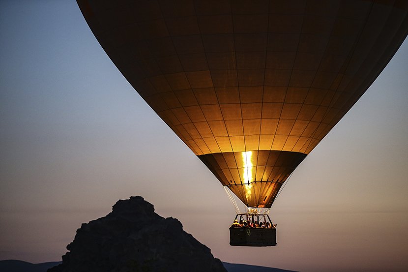 Vazdušni baloni noseći turiste, uzdižu se na nebu u susret izlasku sunca