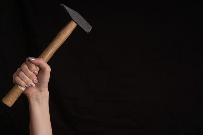 Devojka drži čekić u ruci Devojka drži čekić u ruci