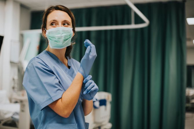 Doktorka stavlja zaštitne rukavice, maska, bolnica Doktorka stavlja zaštitne rukavice, maska, bolnica