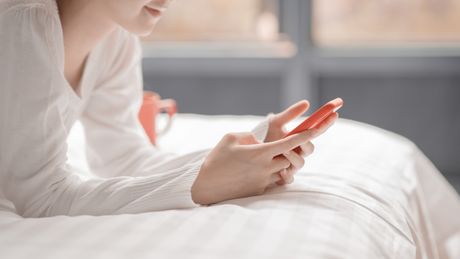 Žena devojka krevet mobilni telefon poruke