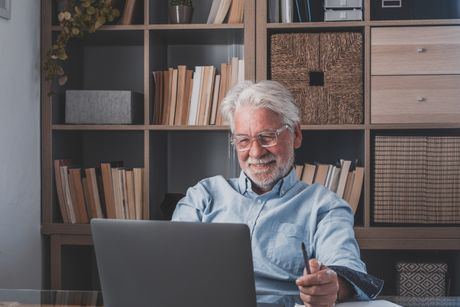 Stariji sed čovek za kompjuterom računarom