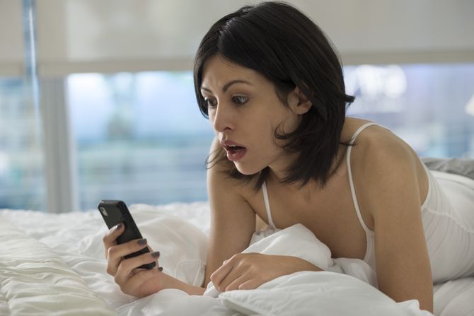 žena, telefon, žena drži telefon, dopisivanje, špiuniranje telefona, šok, ljubavna prepiska iz kreveta