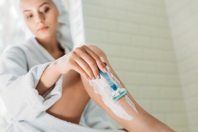 Žena noge brijanje young woman shaving leg in bathroom