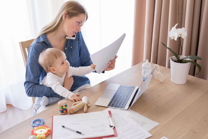 Working mom talking on the phone with child in her lap Mama Beba Rad od kuće Working mom talking on the phone with child in her lap Mama Beba Rad od kuće