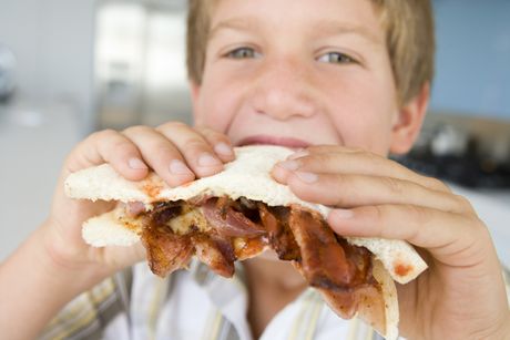 Boy eating bacon sandwich at home dečak sendvič sa slaninom slanina Boy eating bacon sandwich at home dečak sendvič sa slaninom slanina