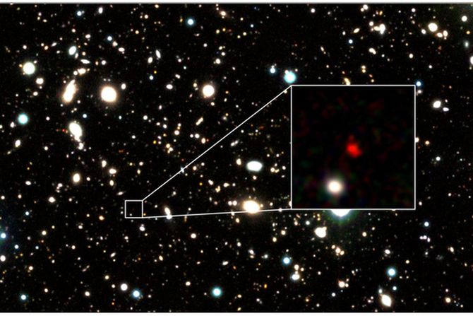 Three-color image of HD1, the most distant galaxy candidate to date, created using data from the VISTA telescope. The red object in the center of the zoom-in image is HD1.