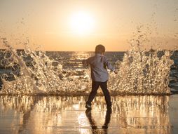 Dečak se igra obučen na plaži predveče
