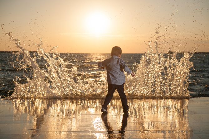 Dečak se igra obučen na plaži predveče