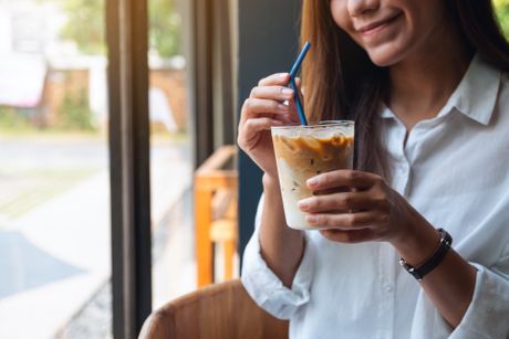 Devojka pije ledenu kafu kafa plastična slamčica