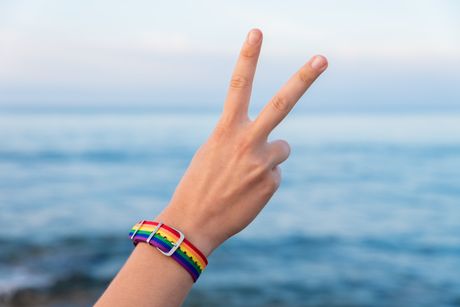Hand of a person in a colorful bracelet gesturing the V sign