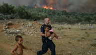 Policajac nosi dečaka u naručju dok iza njih bukti požar: Dramatične fotografije iz Grčke obišle svet