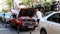 Čovek u centru grada spustio usisivač na trotoar, pa čisti auto dok kabal visi s terase