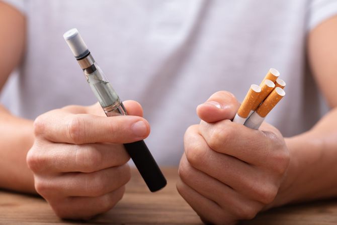 E cigarete, Čovek drži cigaretu za vape i duvan iznad stola