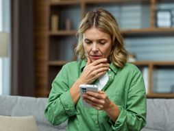 Zabrinuta žena gleda mobilni telefon