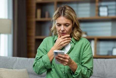 Zabrinuta žena gleda mobilni telefon Zabrinuta žena gleda mobilni telefon