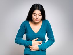 Žena, drži se za stomak