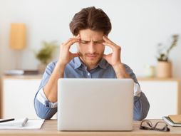 Rad od kuće, glavobolja, posaolaptop, stres, muškarac se drži za glavu