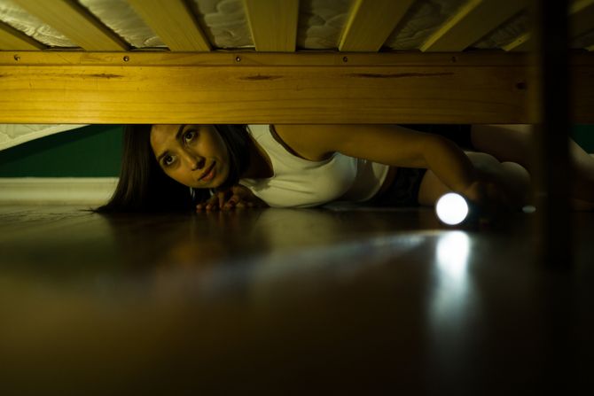 Žena  gleda ispod kreveta Žena  gleda ispod kreveta