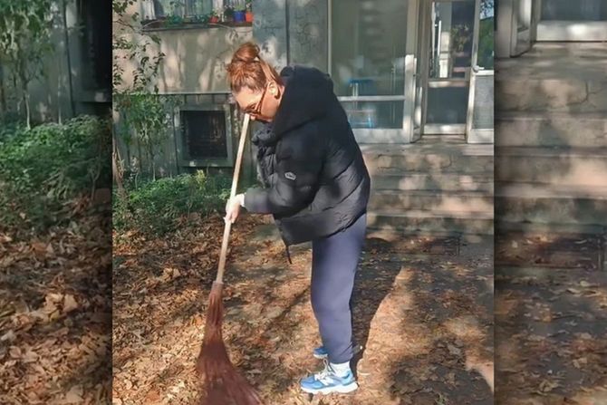 Natalija čisti lišće ispred zgrade