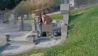 ZANELI SE NA GROBLJU! Muškarac potpuno nag, a žena sedi na nadgrobnom spomeniku: Snimak sve zgrozio
