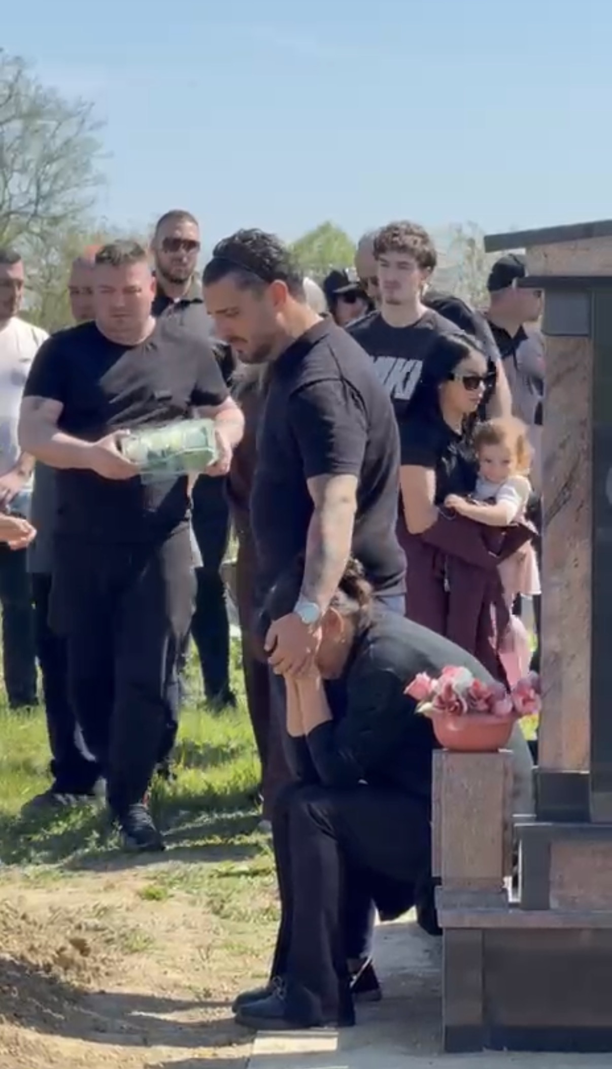 Majka Branka jeca sedi kod Draganovog groba i jeca, Darko je mazi po glavi: