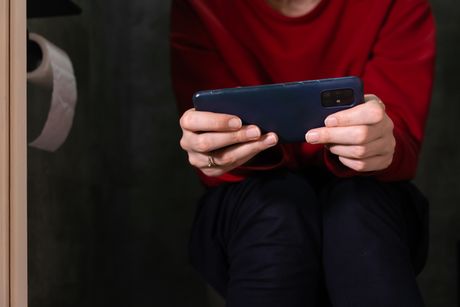 Žena koristi mobilni telefon u toaletu
